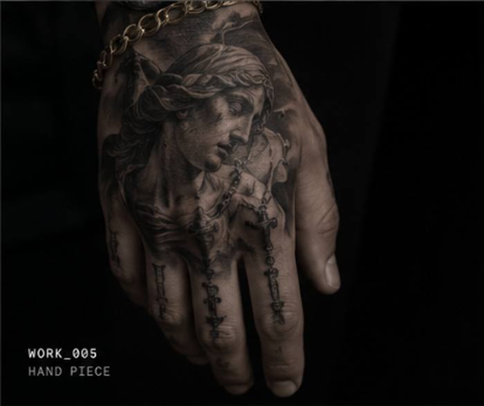 Black and grey tattoo of a woman's portrait with rosary beads, back of the hand